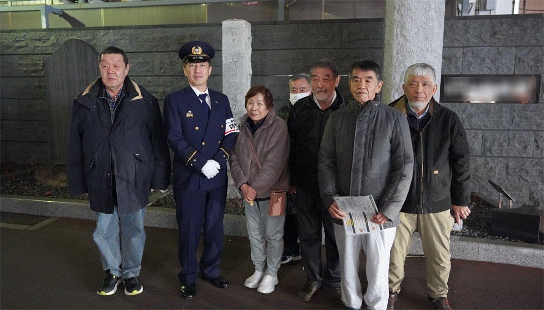 町会事務所前にて消防署の方々と記念写真の画像